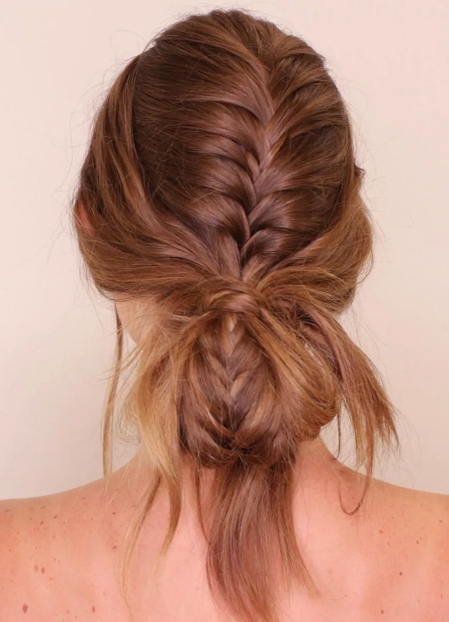 Femme aux cheveux lisses coiffée en tresse française terminée en chignon bas, de dos