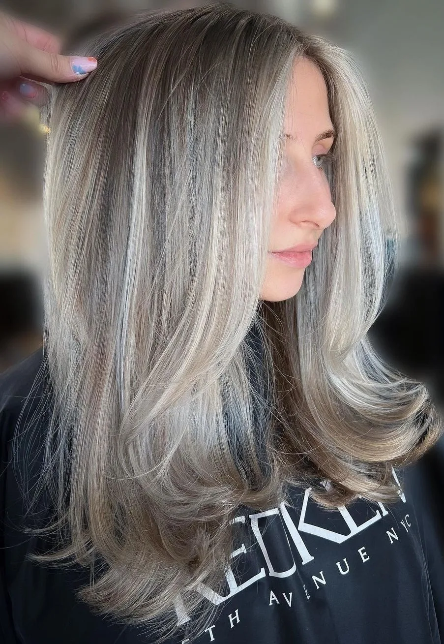 Femme aux longs cheveux lisses volumineux avec de légères couches, de profil