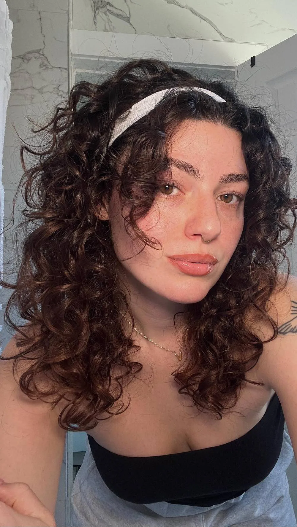 Femme avec un bandeau blanc noué sur cheveux bouclés, de face