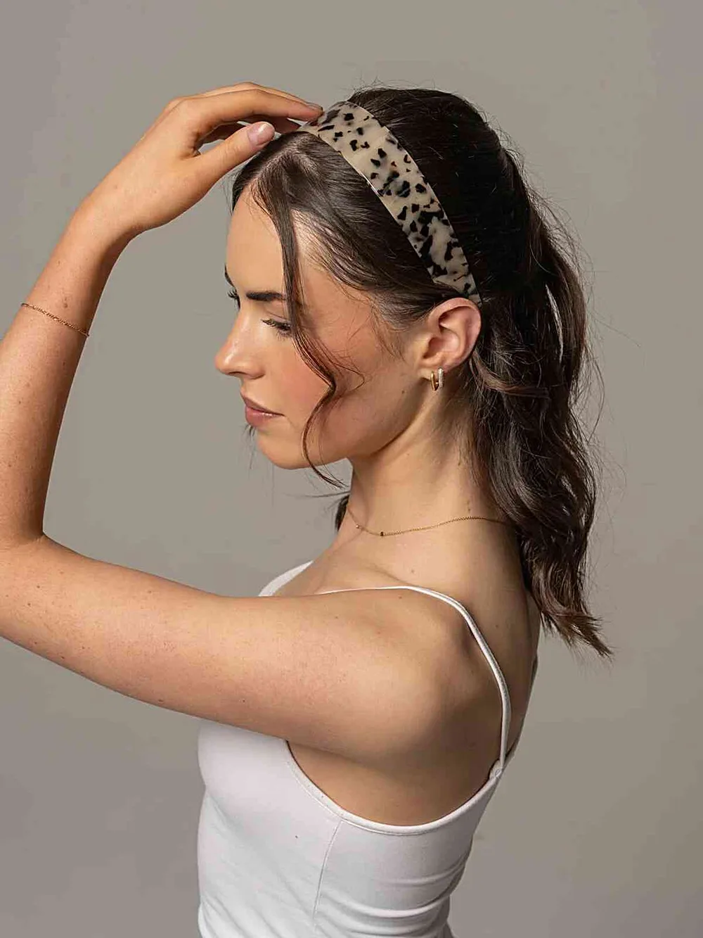 Femme avec un bandeau fin orné et une queue de cheval haute, de profil