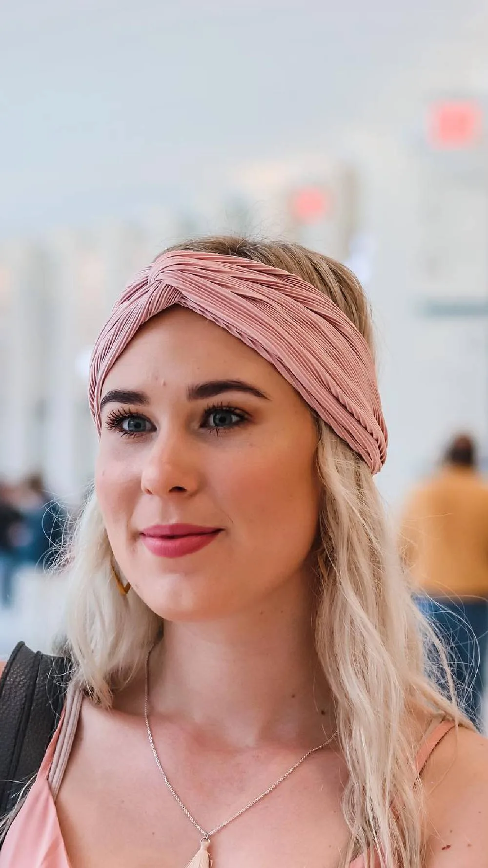 Femme avec un bandeau torsadé rose sur un carré bouclé court, de face