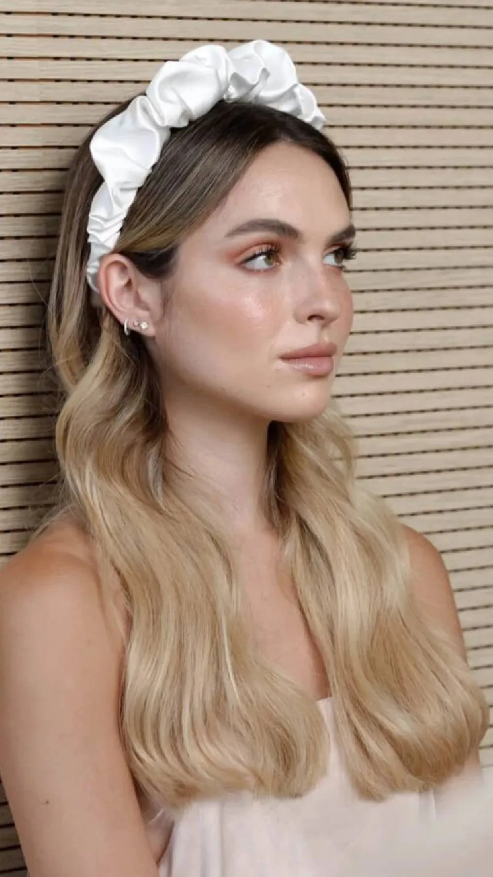 Femme avec un serre-tête à perles blanches et de longues ondulations blondes, de face