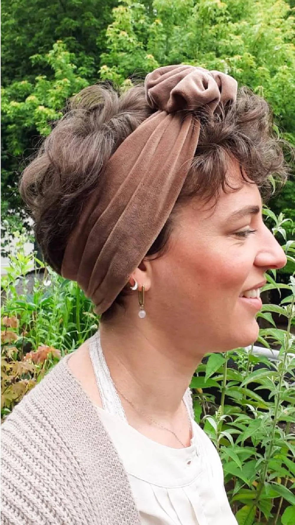 Femme avec un turban en velours rouille noué et cheveux relevés, de profil