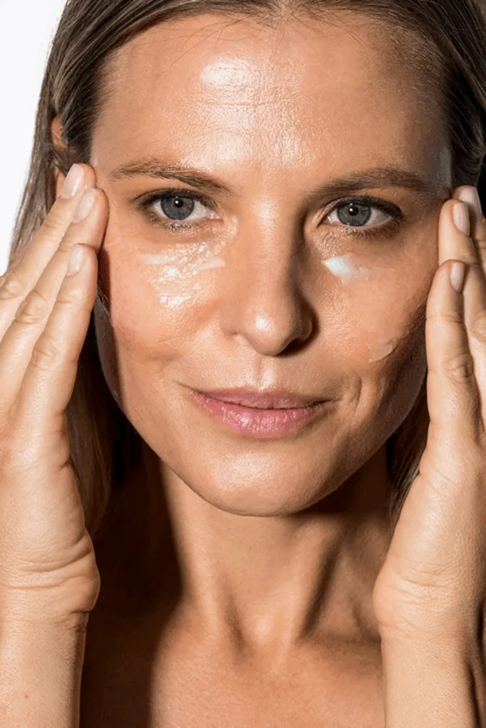 Femme d'une quarantaine d'années appliquant une crème de soin sur son visage