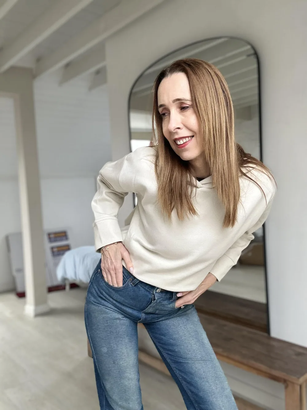 Femme de 60 ans en pull écru simple et jean droit bleu