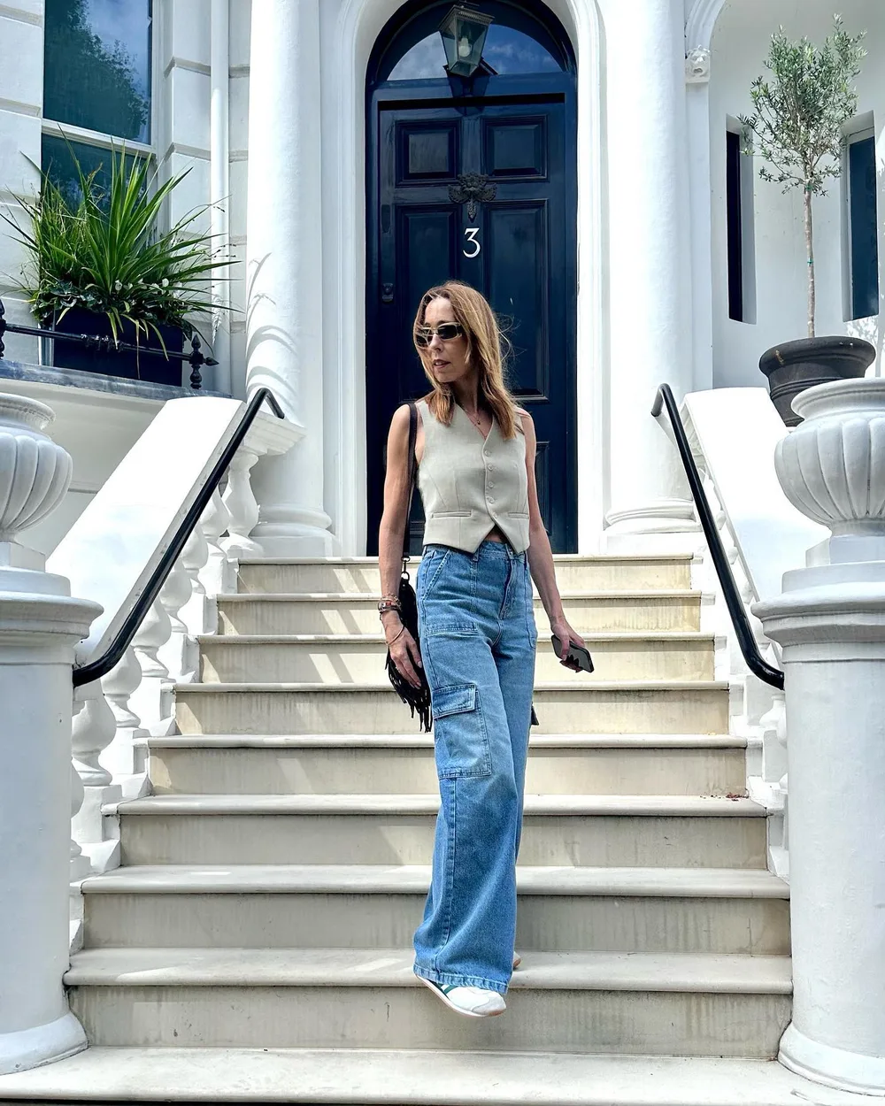 Femme de 60 ans portant un gilet tailleur beige avec un jean large bleu