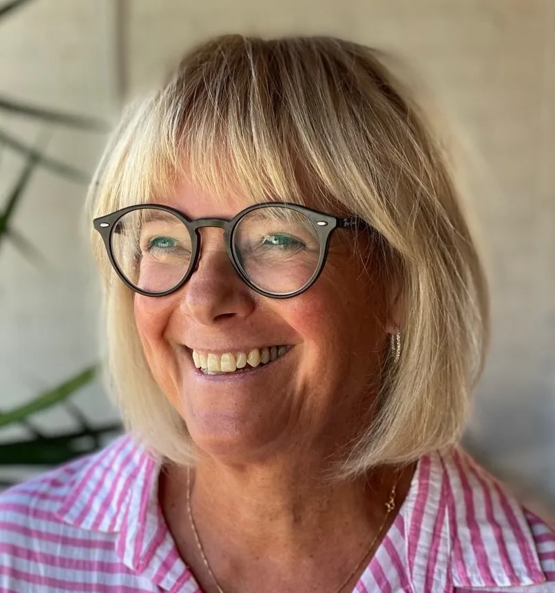 Femme de 70 ans avec carré blond et lunettes, sourire, de face