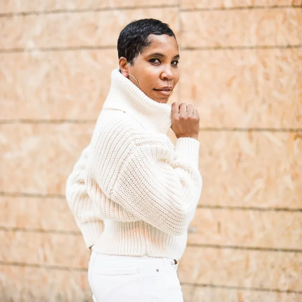 Femme élégante en gros col roulé blanc et pantalon clair ton sur ton