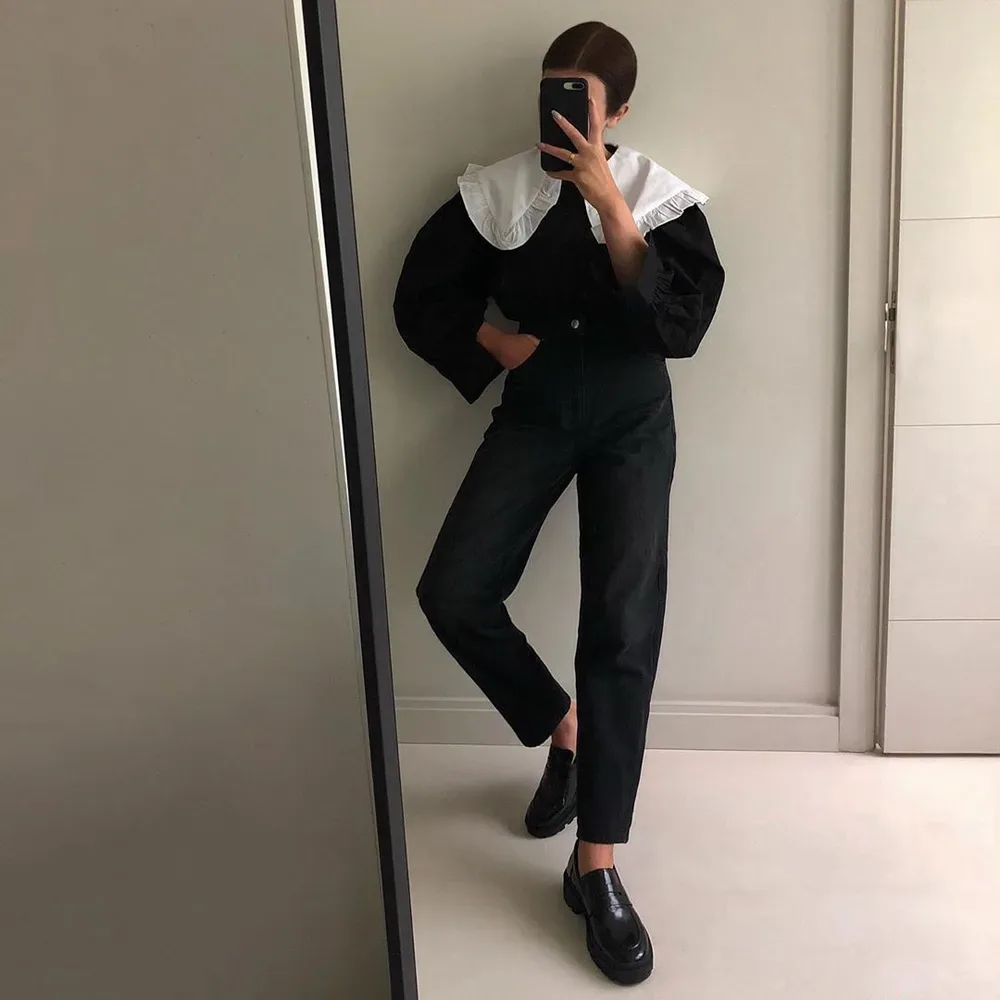 Femme élégante en tenue noire avec grand col blanc graphique