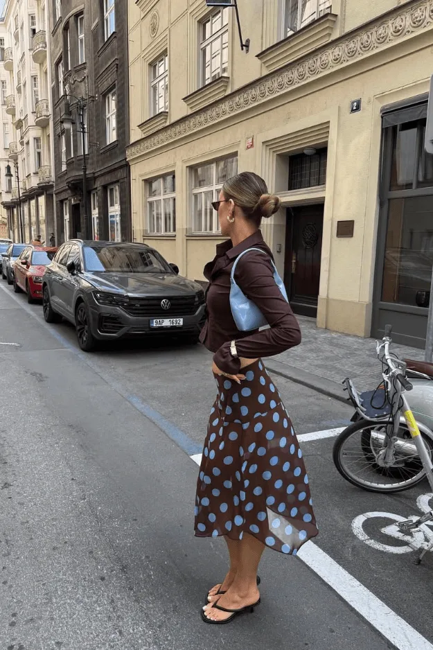 Femme en jupe midi fluide imprimée et bottes, look féminin chic