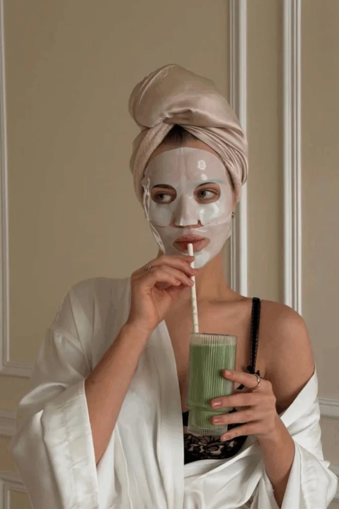 Femme en masque tissu buvant un smoothie vert vitamine