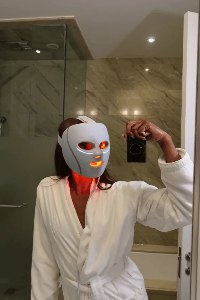 Femme en peignoir portant un masque de luminothérapie LED lumineux
