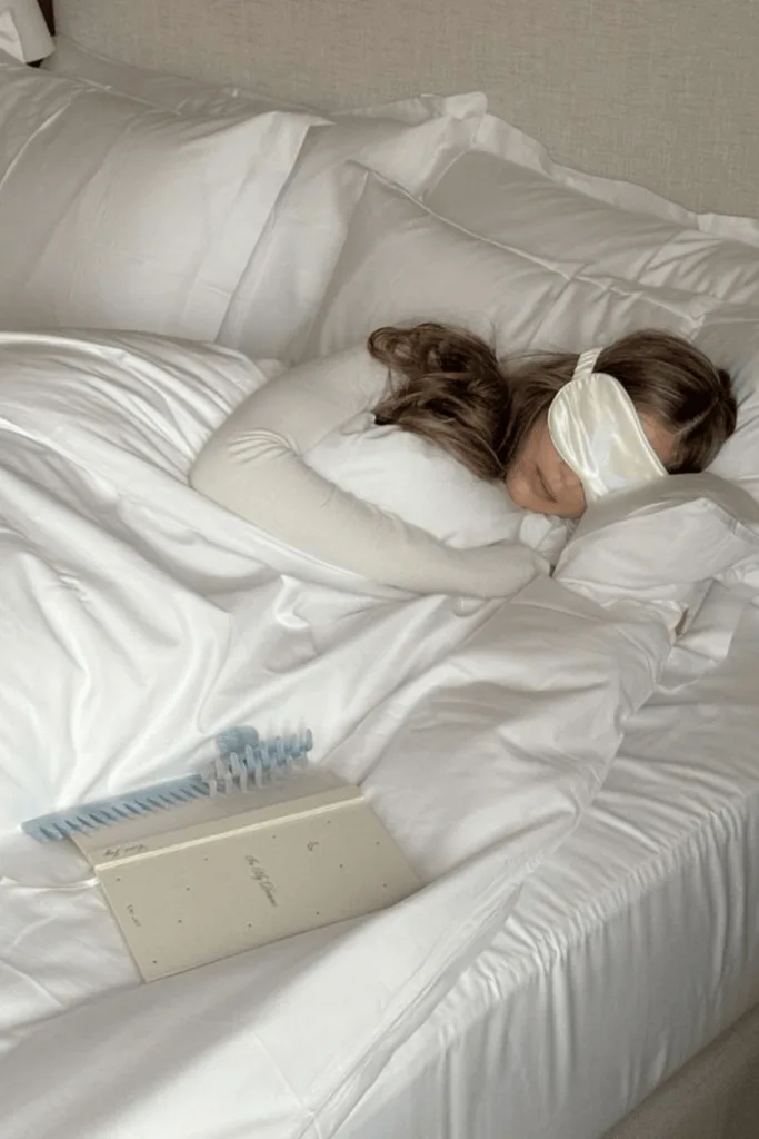 Femme endormie paisiblement dans un lit blanc, masque de nuit à côté