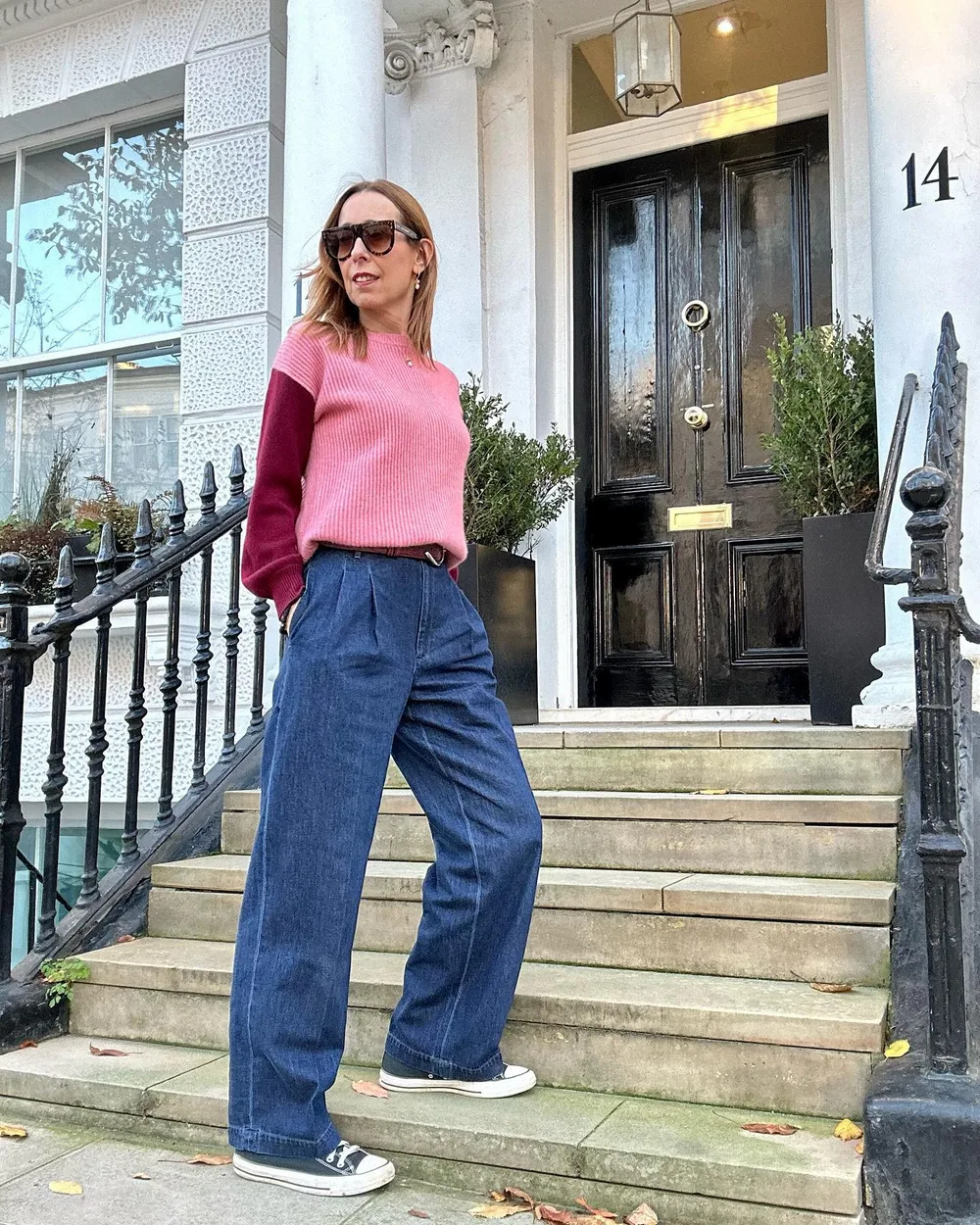 Femme mûre en pull rose, jean très large et baskets blanches