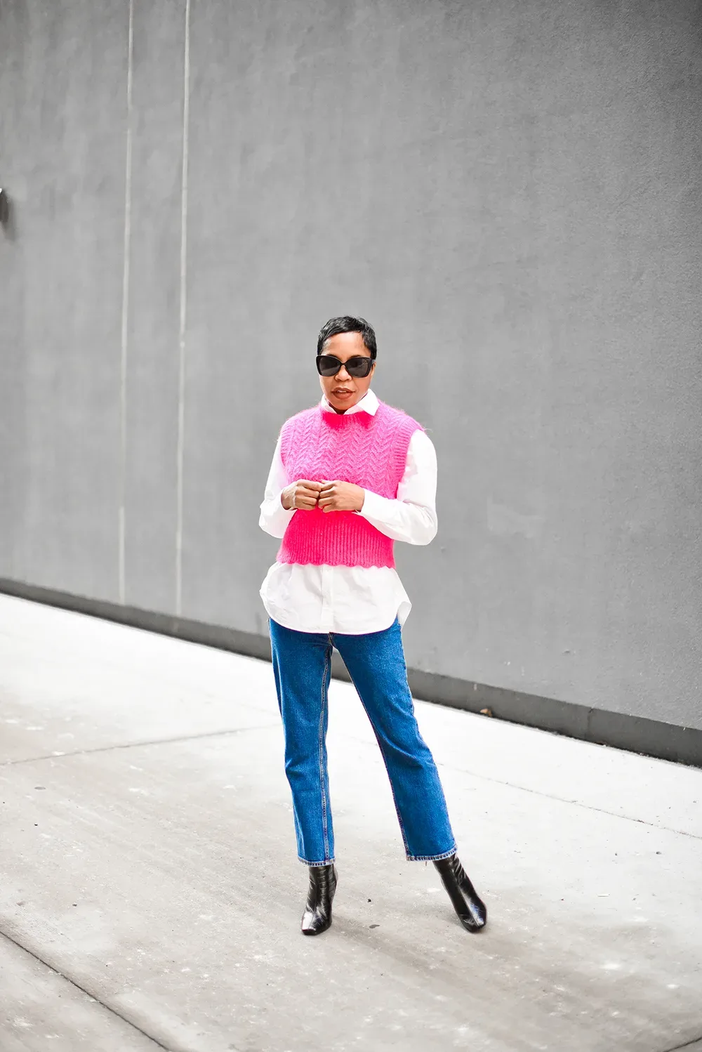 Femme mûre en pull sans manches rose sur chemise blanche et jean