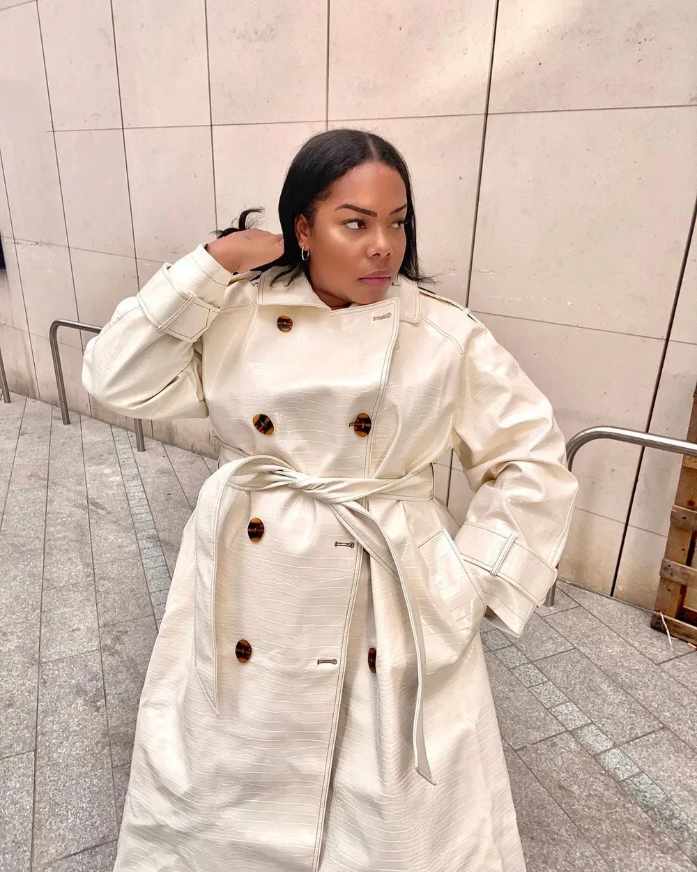Femme mûre portant un trench clair noué à la taille avec bottines