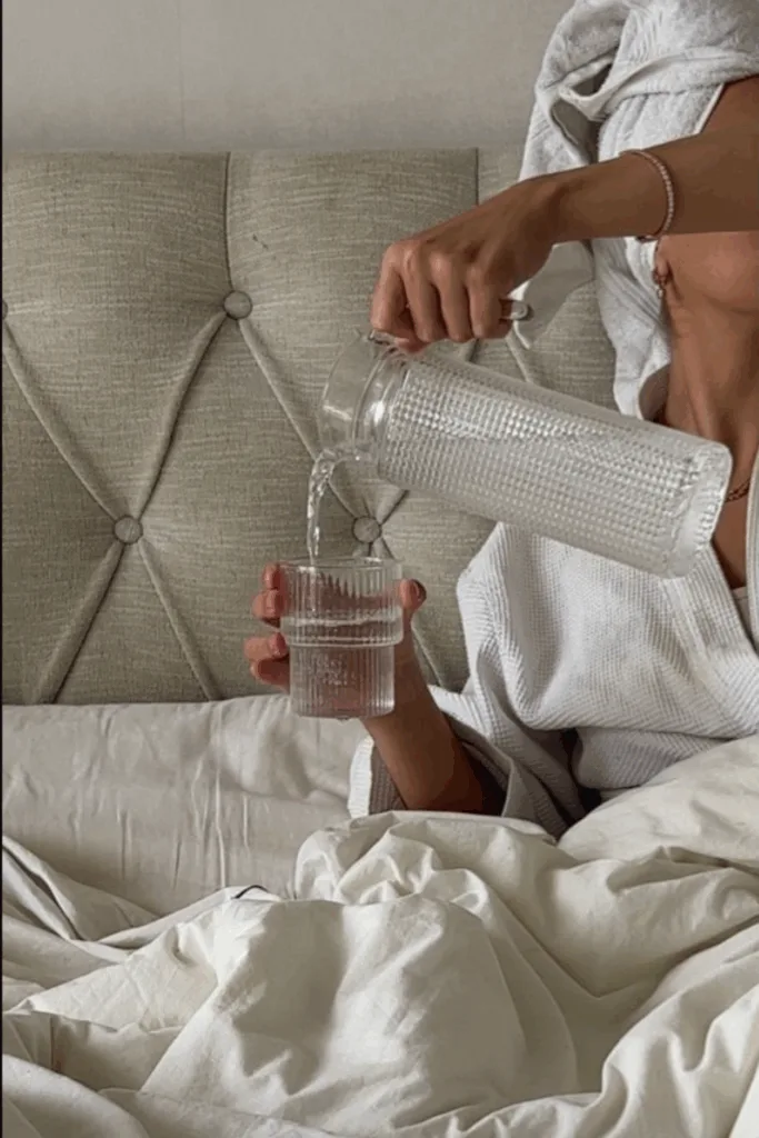 Femme se servant un grand verre d'eau au réveil dans son lit