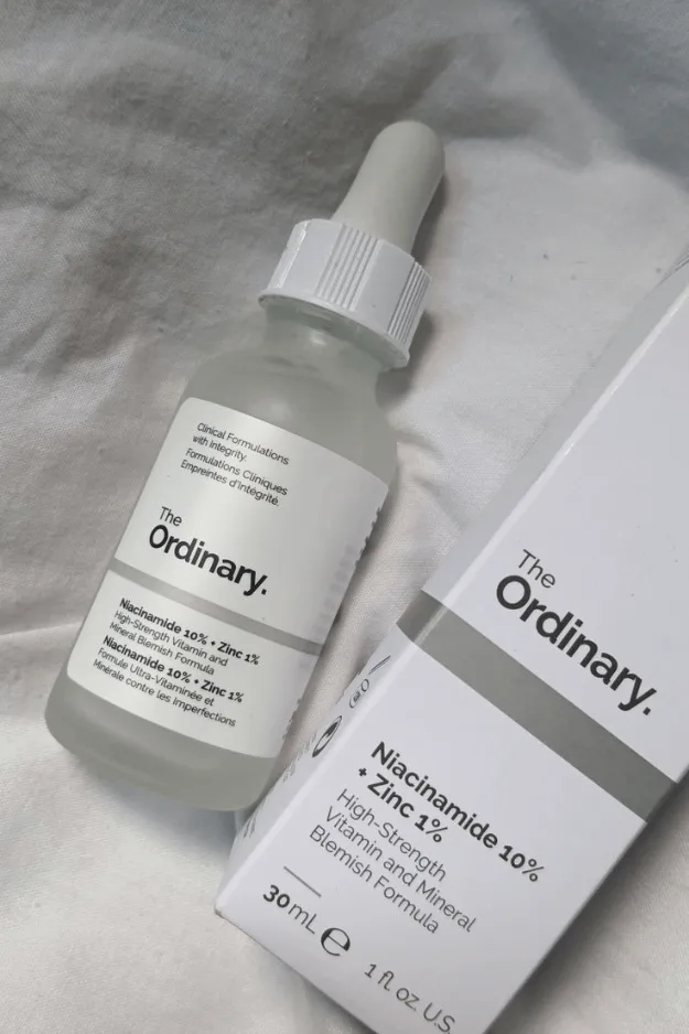 Flacon de sérum à la niacinamide posé sur un tissu clair