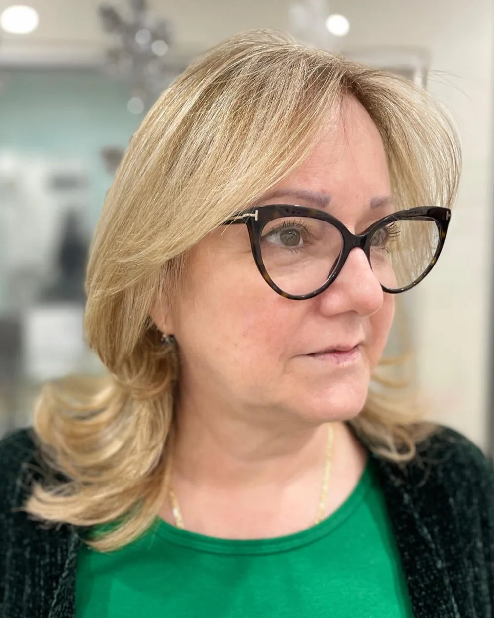 Frange rideau blonde sur dégradé effilé, femme de 60 ans à lunettes