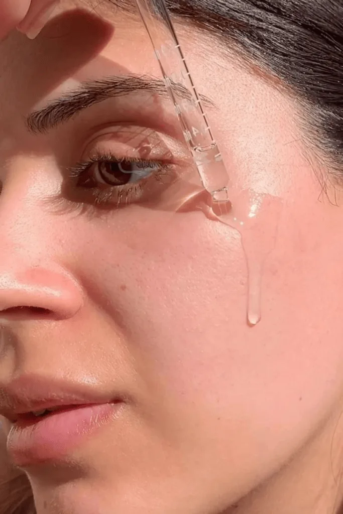 Gros plan sur une peau dewy avec une goutte de sérum qui perle