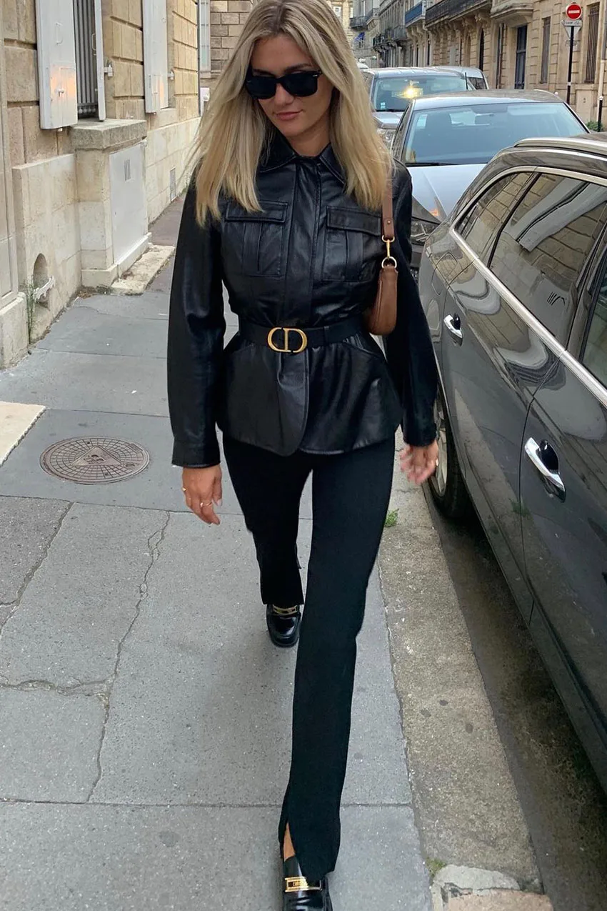 Jean noir bootcut avec veste en cuir noire ceinturée et sac porté épaule