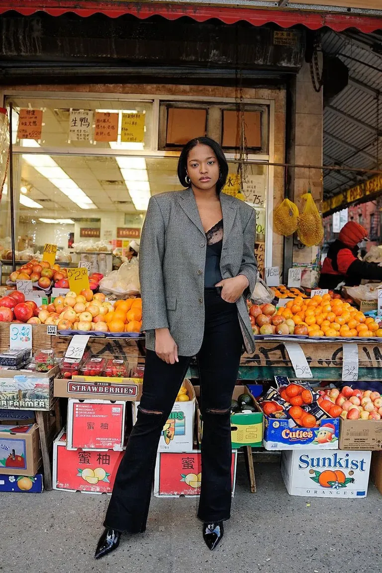 Jean noir droit porté avec un blazer gris oversize et des bottines pointues