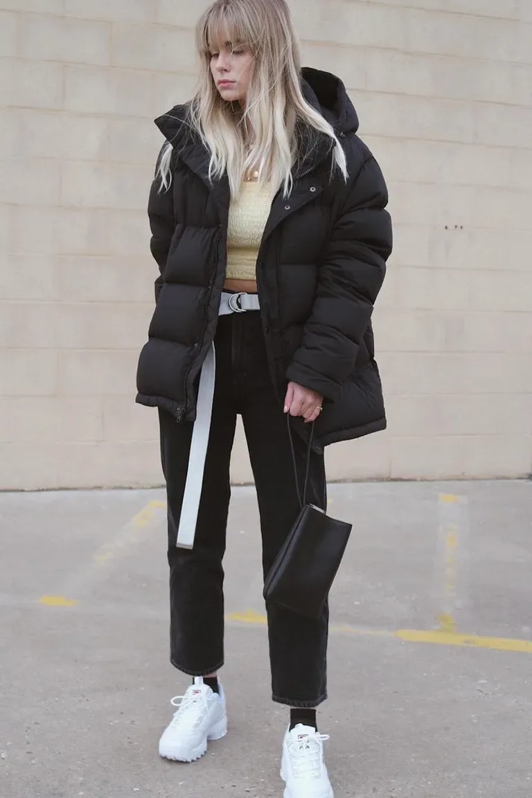 Jean noir porté avec un haut sombre et une ceinture blanche contrastante