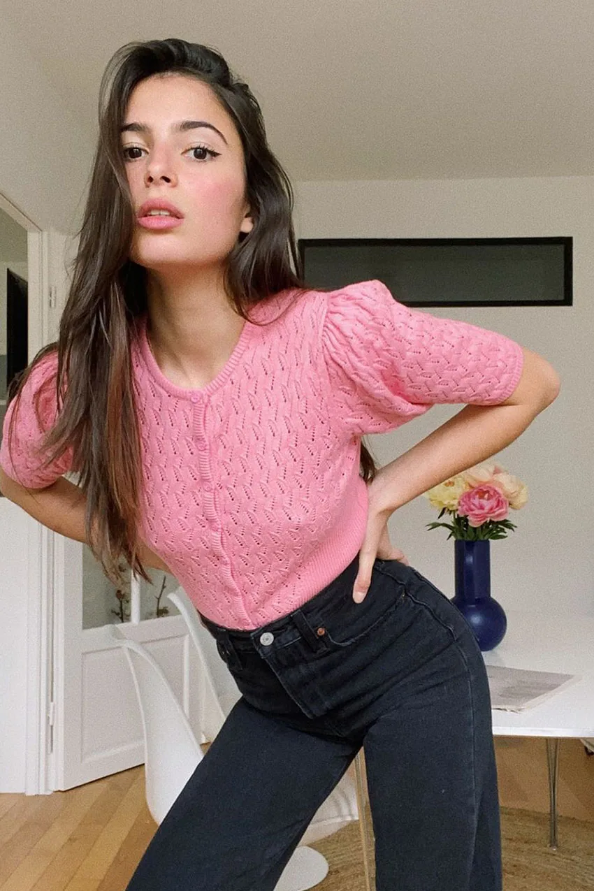 Jean noir taille haute porté avec un pull rose court en maille