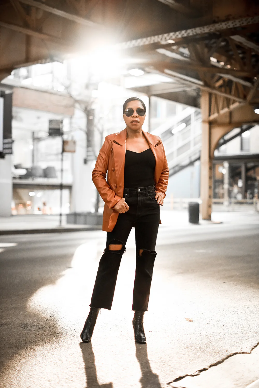 La veste cognac sur un total look noir portée par une femme élégante