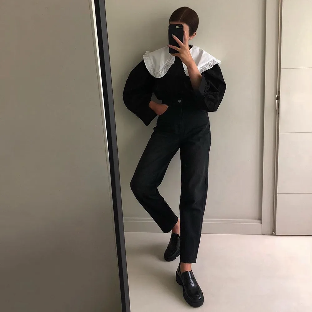Le col blanc graphique sur une tenue noire portée par une femme élégante