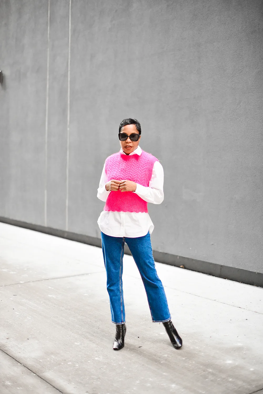 Le pull rose superposé sur une chemise blanche portée par une femme élégante