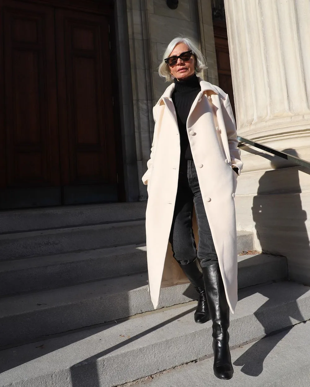 Le trench clair avec un jean slim et des bottes portée par une femme élégante
