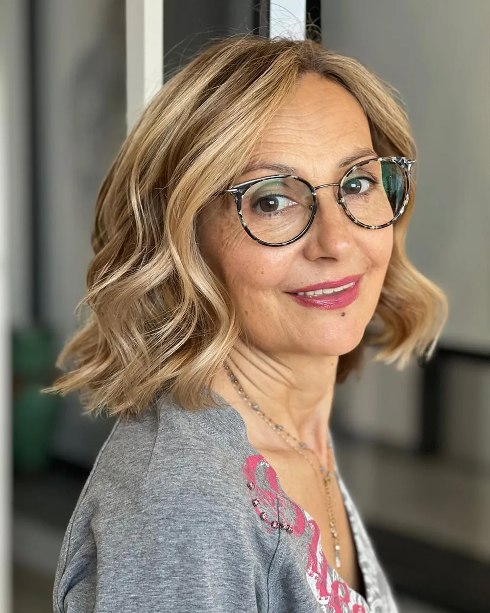 Lob blond ondulé avec lunettes rondes sur femme de la soixantaine