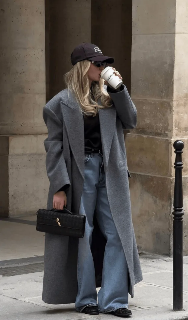 Long manteau gris oversize porté avec un jean large et une casquette