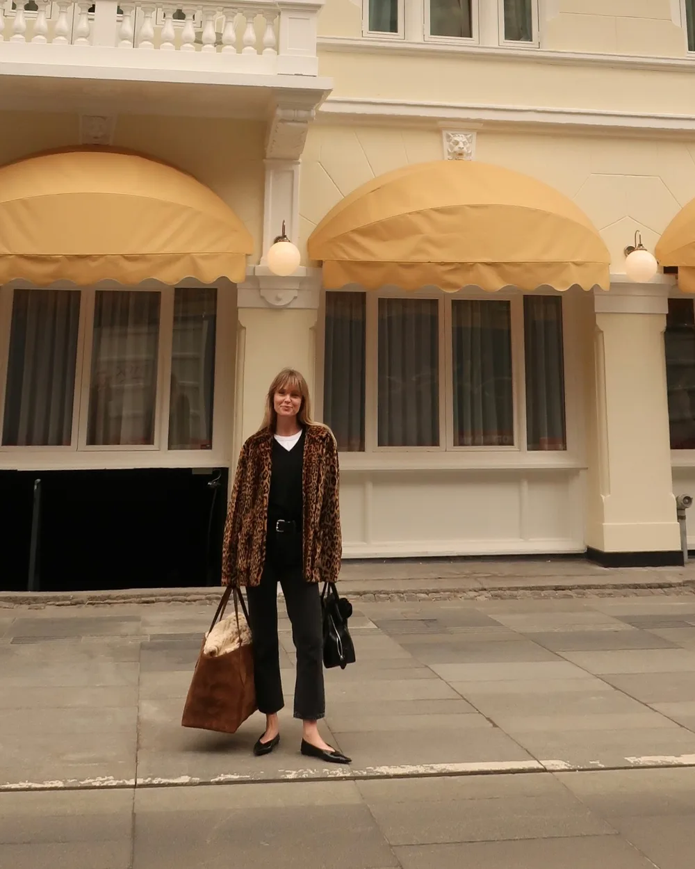 Long manteau léopard porté avec un pantalon brun et des accessoires noirs