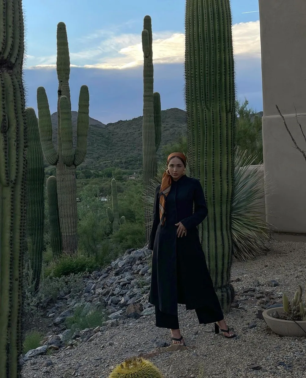 Long manteau noir superposé à une tunique et un pantalon noir ample