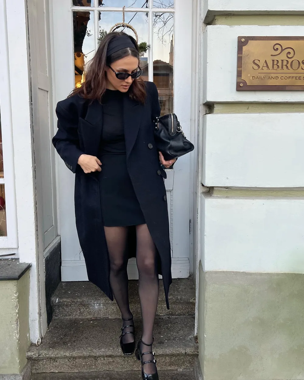 Manteau bleu marine sur robe courte noire avec collants et babies