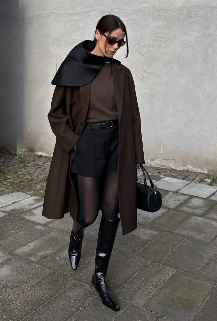 Manteau chocolat avec short noir, collants et bottes à petit talon