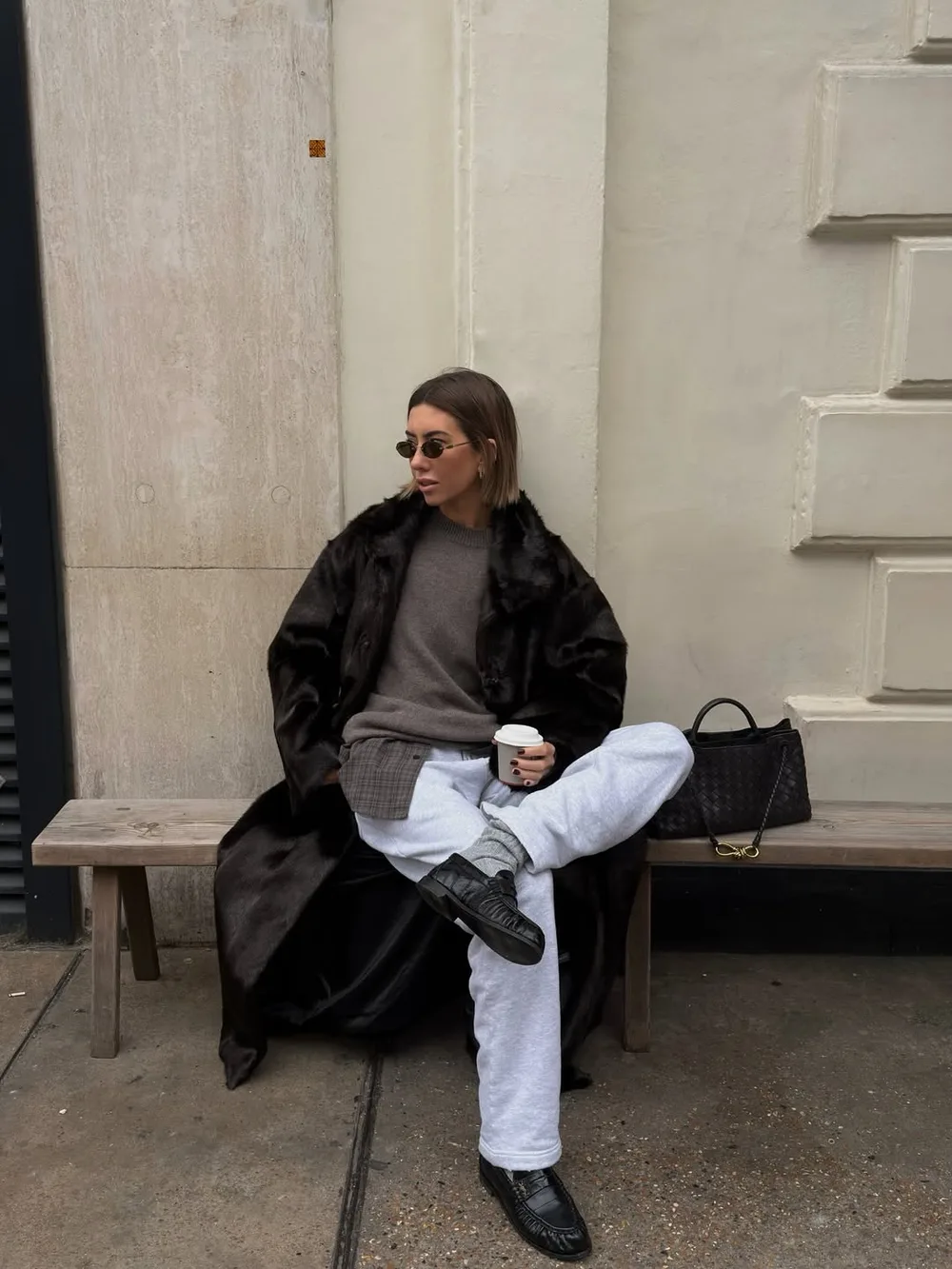Manteau en fausse fourrure sombre porté avec un jean blanc et des mocassins noirs