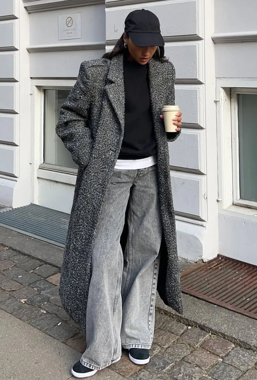 Manteau long gris avec jean large, baskets et casquette noire