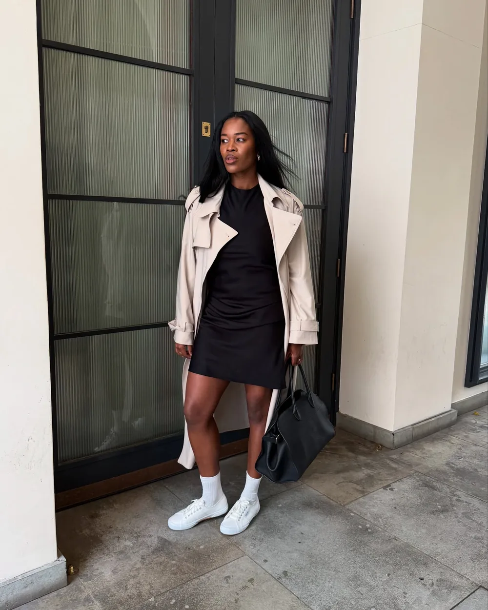 Mini-robe noire avec trench beige, chaussettes blanches et baskets