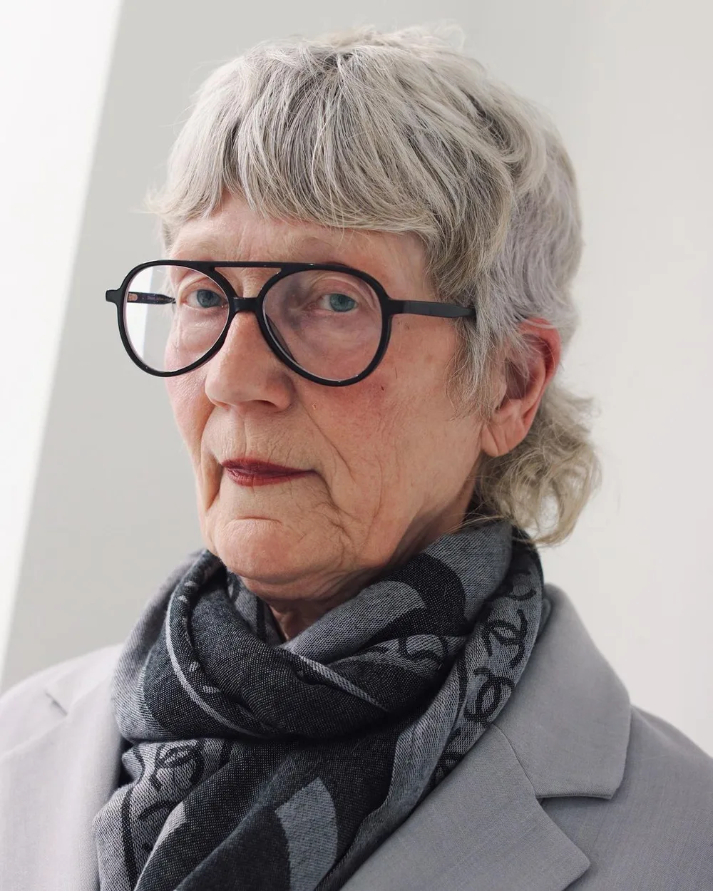 Mullet shaggy gris grisonnant sur femme de 60 ans avec lunettes rondes
