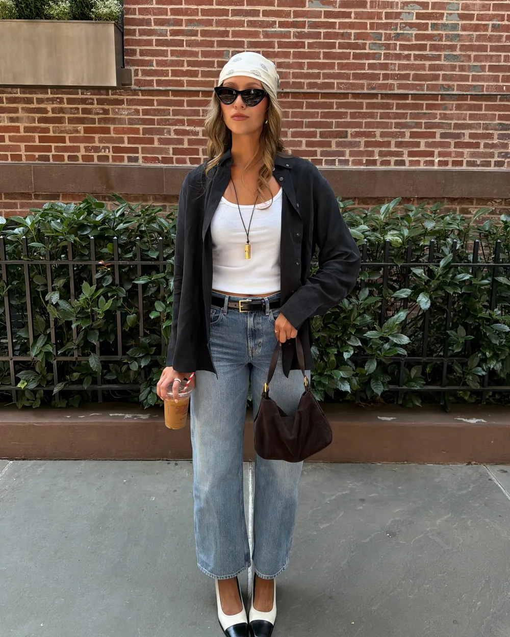 Petit sac d'épaule en daim marron porté avec un blazer noir et un jean