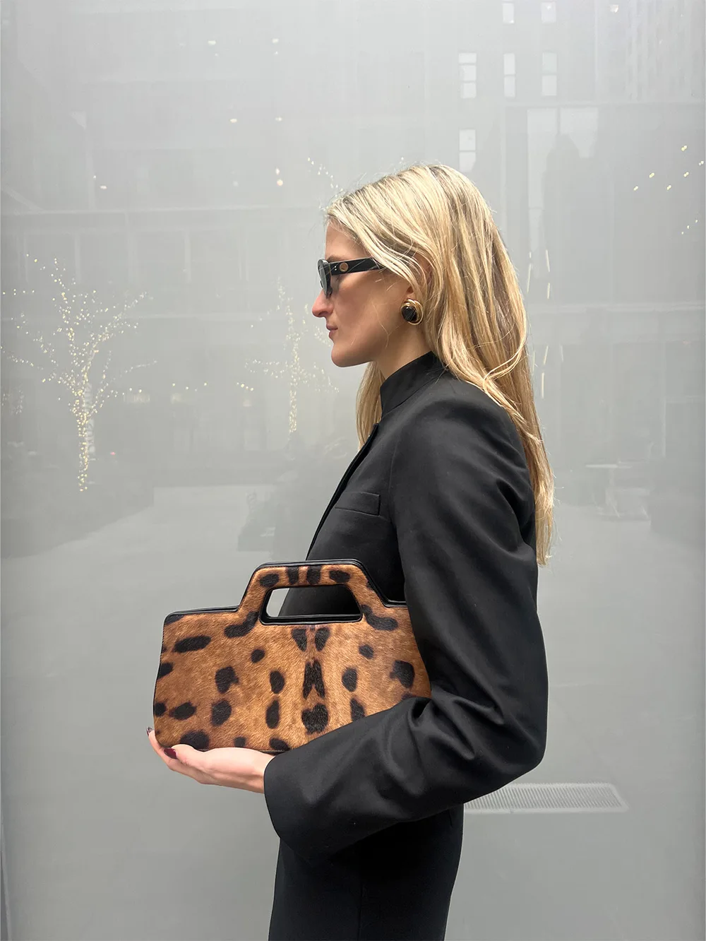Petit sac léopard rigide porté avec un costume noir