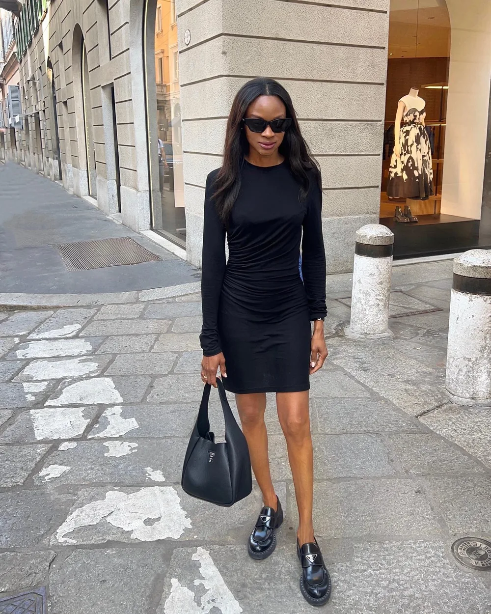 Petite robe noire moulante portée avec des mocassins noirs vernis
