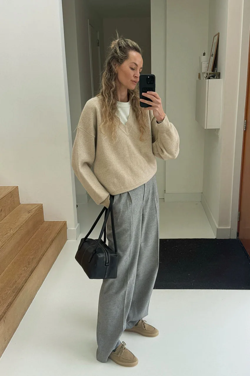 Pull beige superposé sur un tee-shirt blanc avec pantalon gris fluide