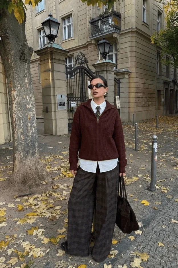 Pull bordeaux col V porté sur une chemise blanche avec un pantalon à carreaux