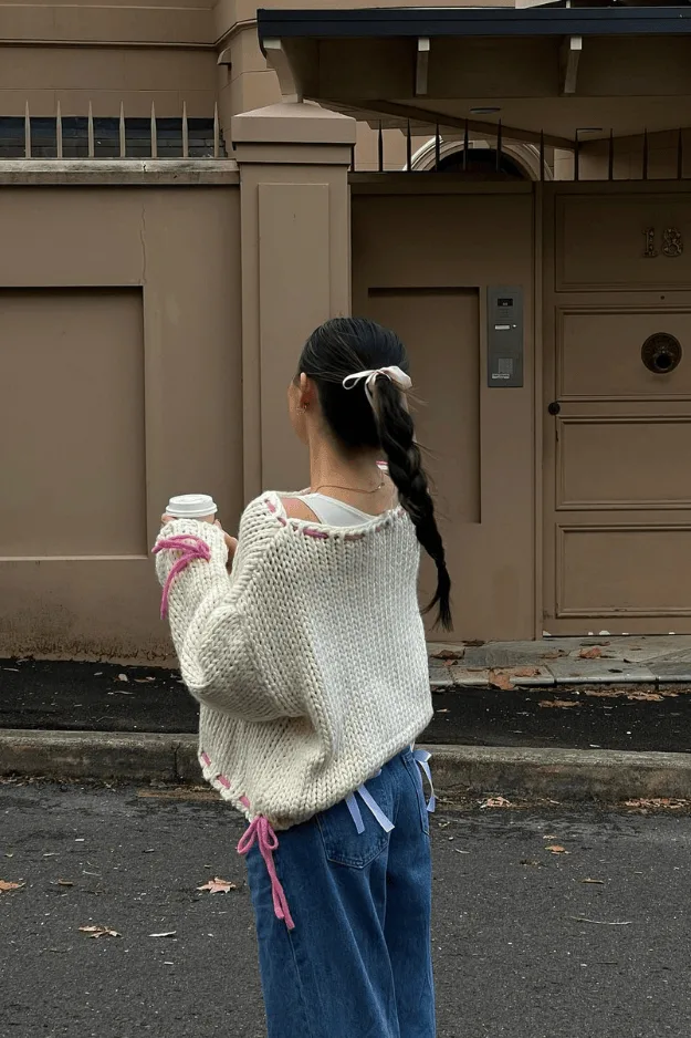 Pull crème orné de petits nœuds roses, coiffure avec ruban assorti