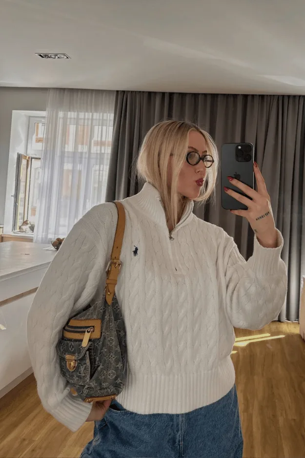Pull écru à torsades et col polo zippé porté avec un jean