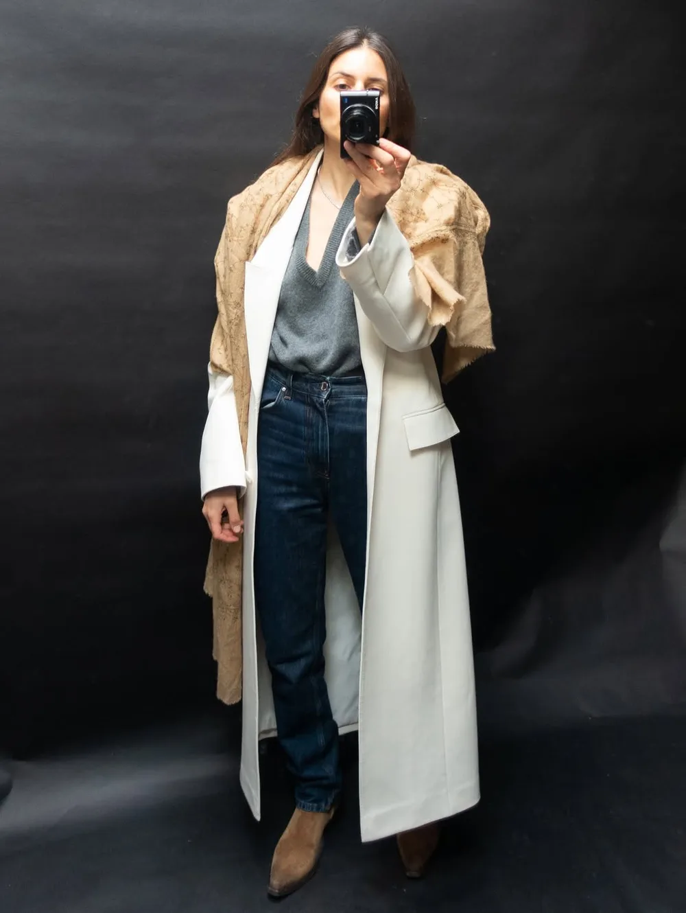 Pull gris avec jean droit, long manteau blanc, écharpe beige et bottines